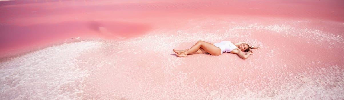 Woman in a pink salt lake banner . She lies in a white bathing suit. Wanderlust photo for memory.