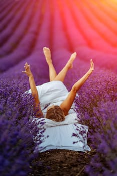 A middle-aged woman lies in a lavender field and enjoys aromatherapy. Aromatherapy concept, lavender oil, photo session in lavender.