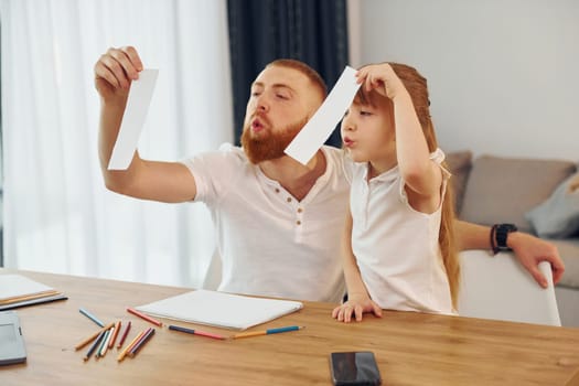 Having fun. Father with his little daughter is at home together.