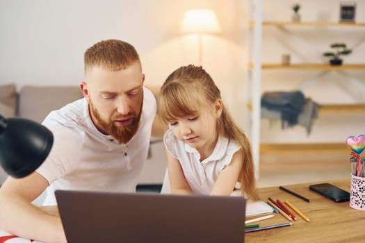 Online learning. Father with his little daughter is at home together.