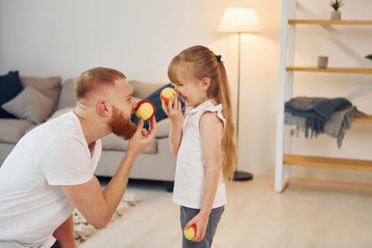 Holding balls. Father with his little daughter is at home together.