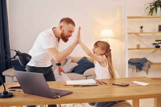 Cozy atmosphere. Father with his little daughter is at home together.