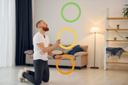 A man in casual clothes throws balls at home.