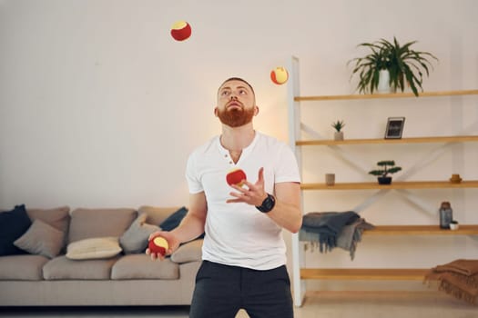 A man in casual clothes throws balls at home.
