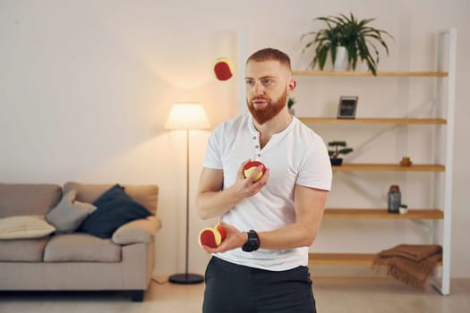A man in casual clothes throws balls at home.