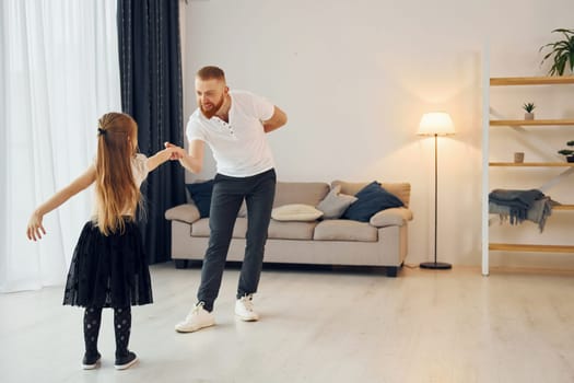 Learning to dance. Father with his little daughter is at home together.