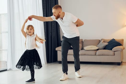 Learning to dance. Father with his little daughter is at home together.