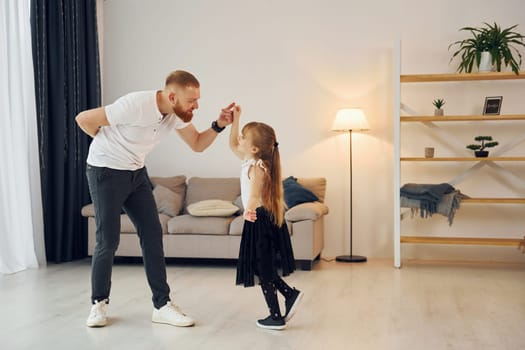 Teaching how to dance. Father with his little daughter is at home together.