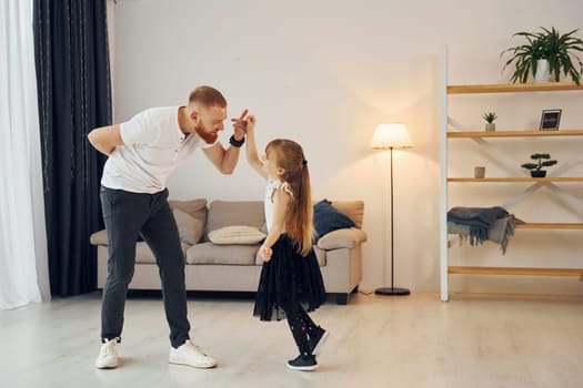 Teaching how to dance. Father with his little daughter is at home together.