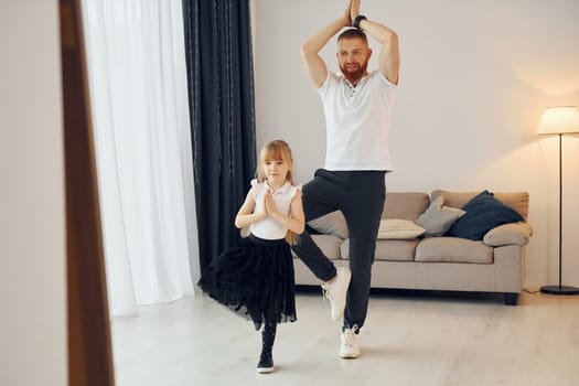 Teaching how to dance. Father with his little daughter is at home together.