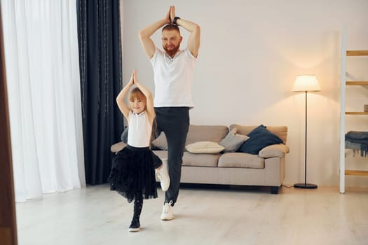 Yoga poses. Father with his little daughter is at home together.