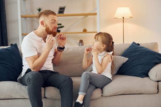 Learning to talk some words. Father with his little daughter is at home together.