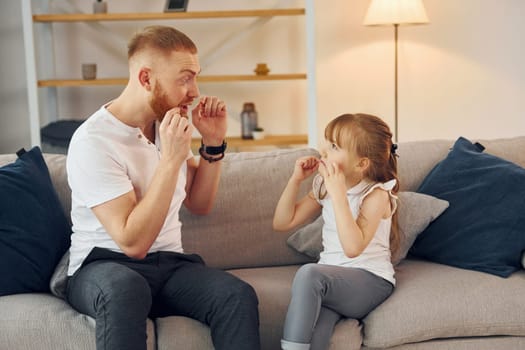 Learning to talk some words. Father with his little daughter is at home together.