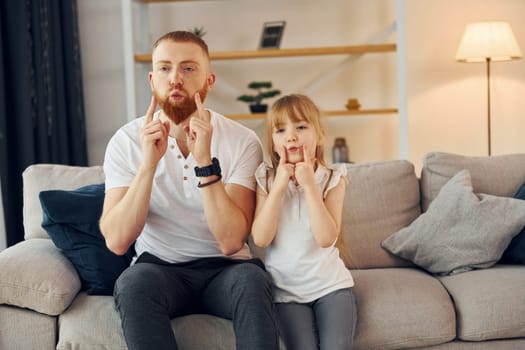 Learning to talk some words. Father with his little daughter is at home together.