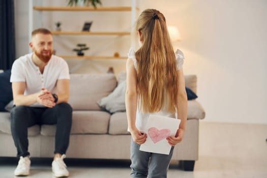 Little girl have gift for man. Father with his little daughter is at home together.