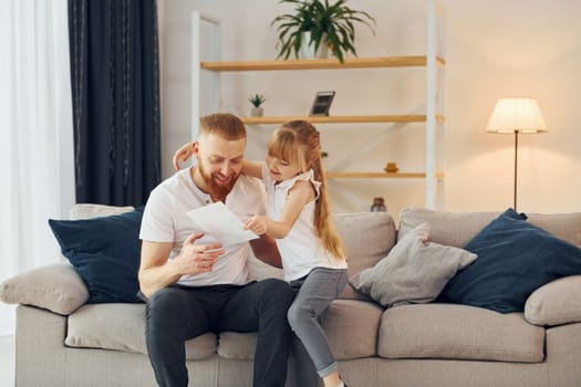 Little girl have gift for man. Father with his little daughter is at home together.