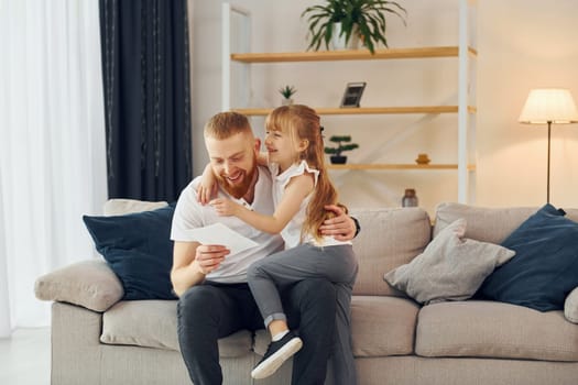 Little girl have gift for man. Father with his little daughter is at home together.