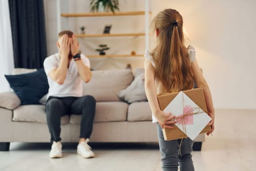 With gift box. Father with his little daughter is at home together.