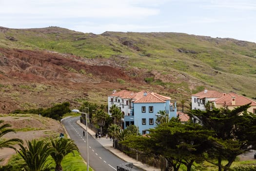 A rural village perched atop a hill, with picturesque architecture and lush trees surrounded by winding roads. Madeira, Portugal