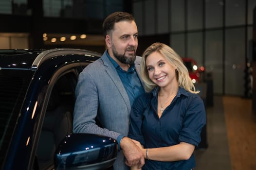Portrait of a happy married couple in a car showroom
