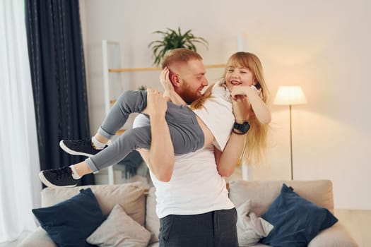 Man holding girl in hands. Father with his little daughter is at home together.