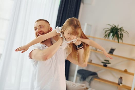 Man holding girl in hands. Father with his little daughter is at home together.