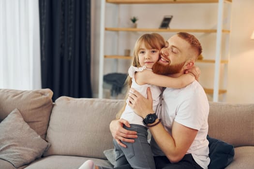 Embracing each other. Father with his little daughter is at home together.