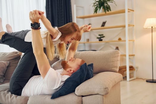 Laying down on the sofa. Father with his little daughter is at home together.