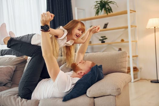 Laying down on the sofa. Father with his little daughter is at home together.