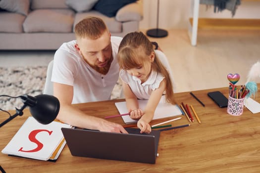 Online learning. Father with his little daughter is at home together.