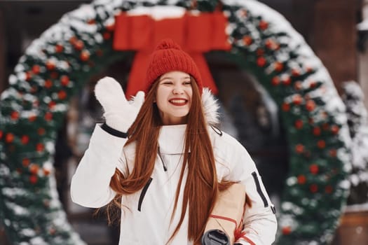 With gift box. Happy young woman standing outdoors and celebrating christmas holidays.