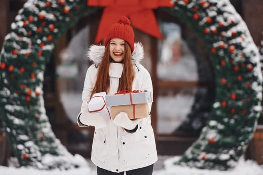 With gift box. Happy young woman standing outdoors and celebrating christmas holidays.