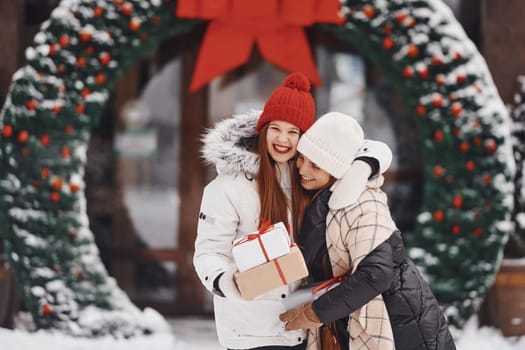 Two young women standing outdoors and celebrating christmas holidays.