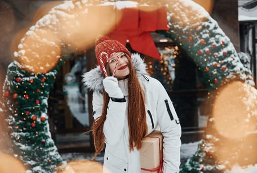 With gift box. Happy young woman standing outdoors and celebrating christmas holidays.