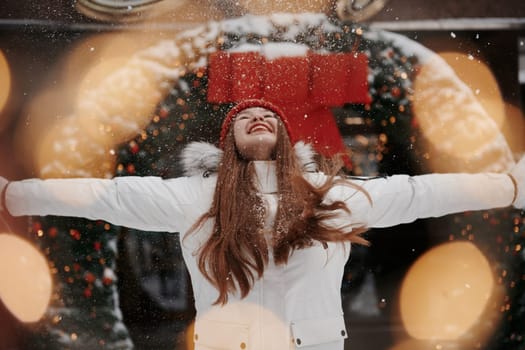 Playing with snow. Happy young woman standing outdoors and celebrating christmas holidays.