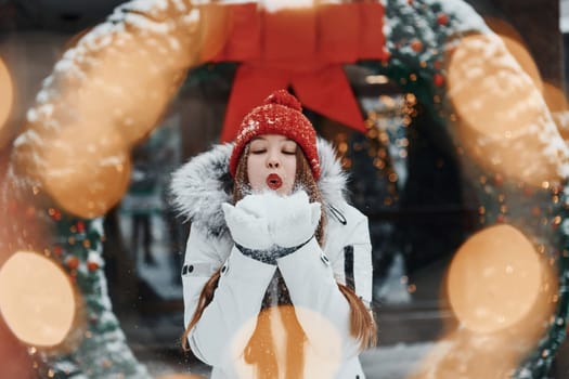 Playing with snow. Happy young woman standing outdoors and celebrating christmas holidays.