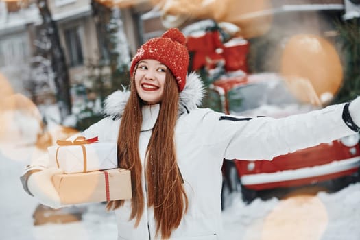 With gift box. Happy young woman standing outdoors and celebrating christmas holidays.