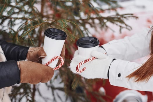 Close up view of women's hands that holding two cups of drink.