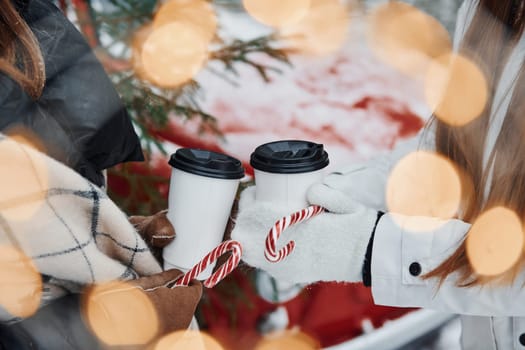 Close up view of women's hands that holding two cups of drink.