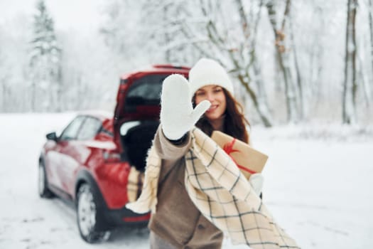 High five, gesture. Beautiful young woman is outdoors near her red automobile at winter time.