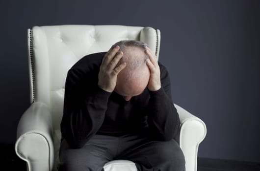 The man is concerned about the problem of hair loss and baldness. He examines his hair on his head.