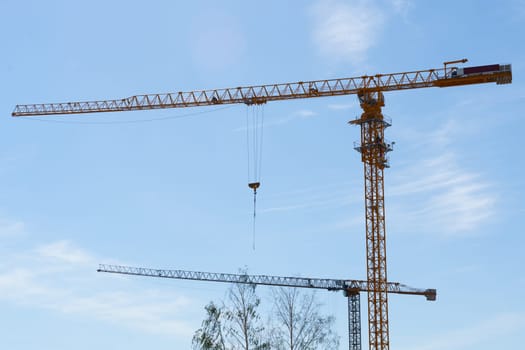 Construction cranes against the blue sky. Bottom view. Building concept.