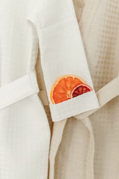 Candied oranges lie in the sleeve of a white robe. Close-up.