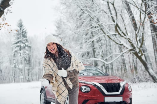 Beautiful nature. Young woman is outdoors near her red automobile at winter time.