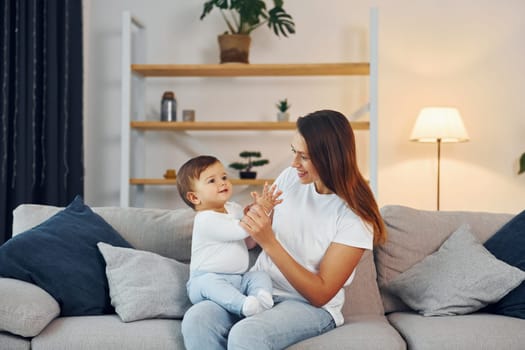 Sitting on the sofa. Mother with her little daughter is at home together.