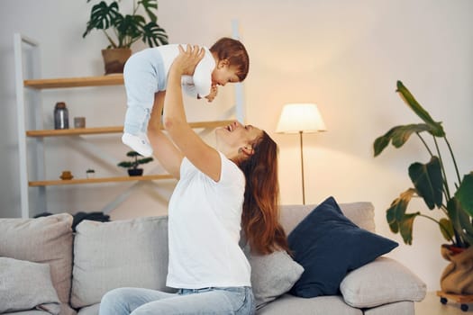 Playing on the sofa. Mother with her little daughter is at home together.