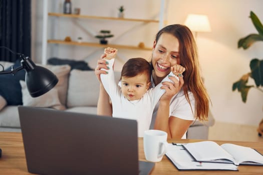 Watching movie by using laptop. Mother with her little daughter is at home together.