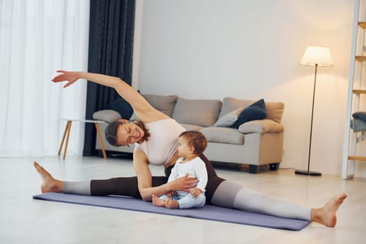 Doing fitness together. Mother with her little daughter is at home together.