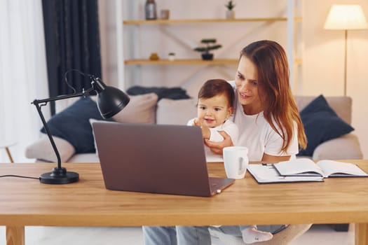 Watching movie by using laptop. Mother with her little daughter is at home together.