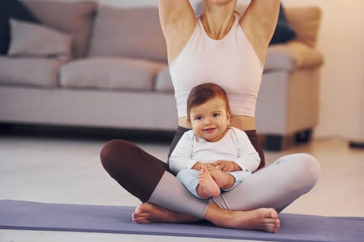 On the yoga mat. Mother with her little daughter is at home together.